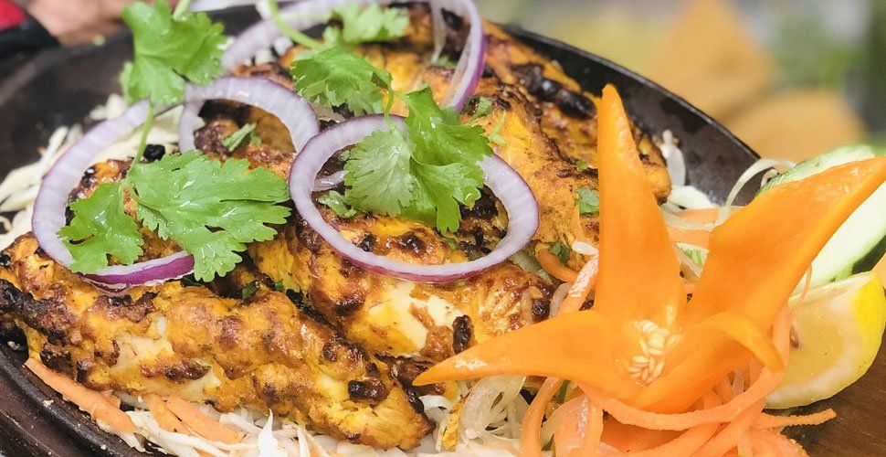 Grilled paneer dish with onions and cilantro, served on shredded vegetables.