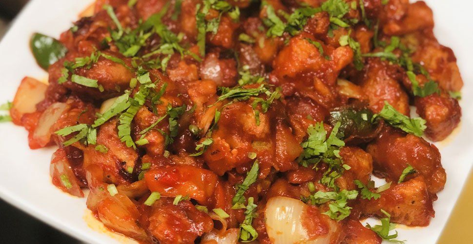 Chicken Manchurian, a stir-fry dish with onions, peppers, and cilantro in a red sauce.