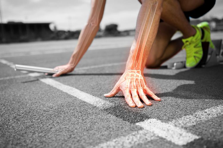 Runner crouched at a track старт line, hands on the ground, with neon green shoes visible.