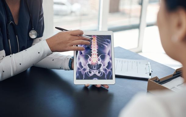 Doctor points to spine X-ray on tablet during a consultation