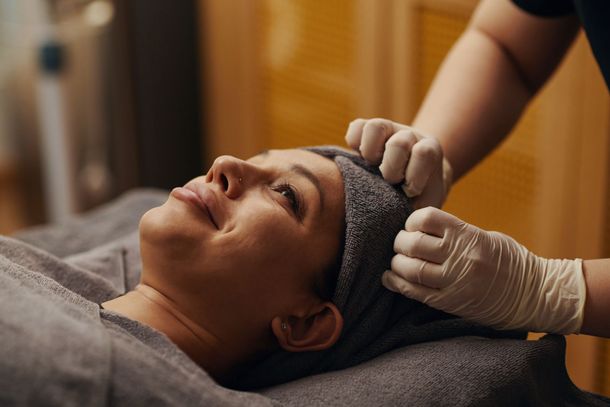 Person receiving a facial massage with gloved hands in a spa setting