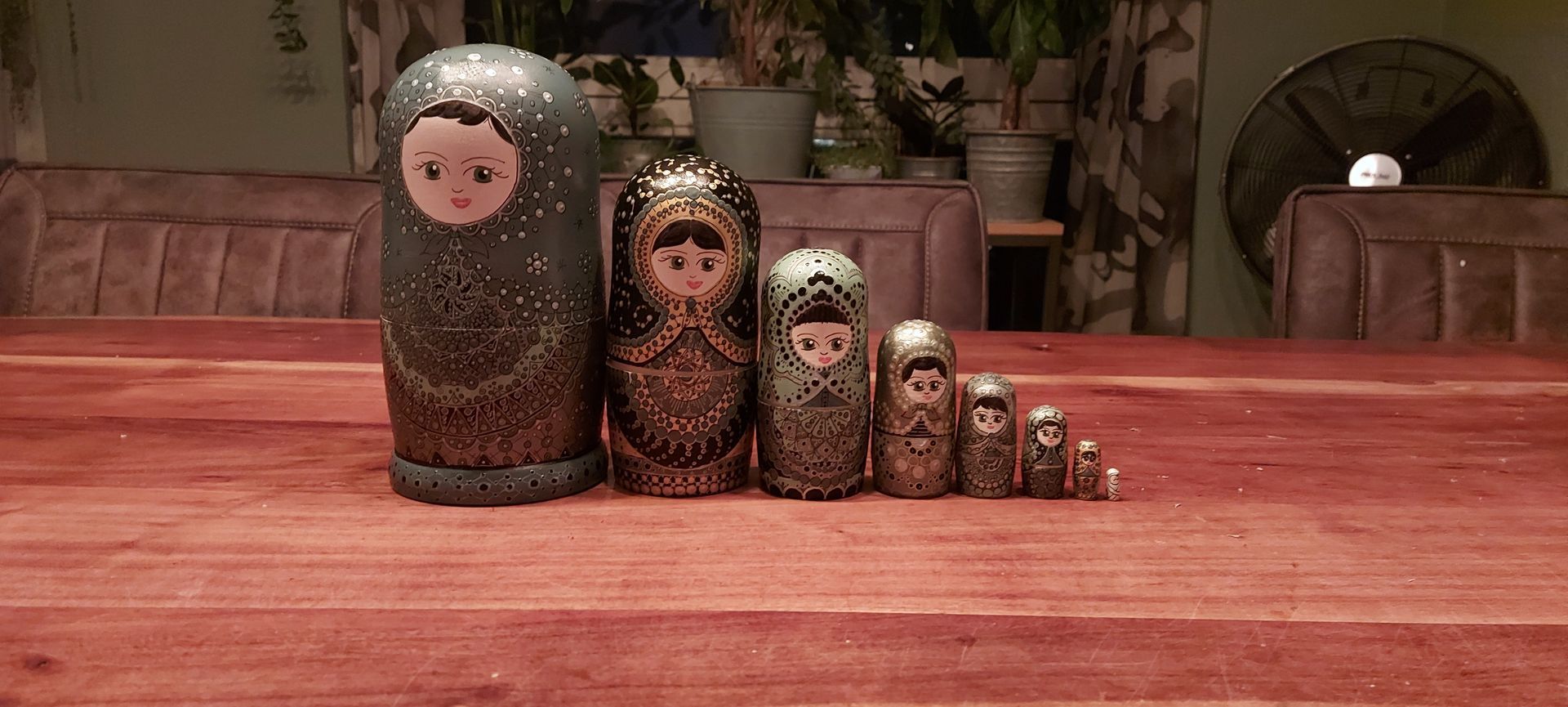 Russische matroesjka-poppen, in een rij op een rode houten tafel, van verschillende groottes.