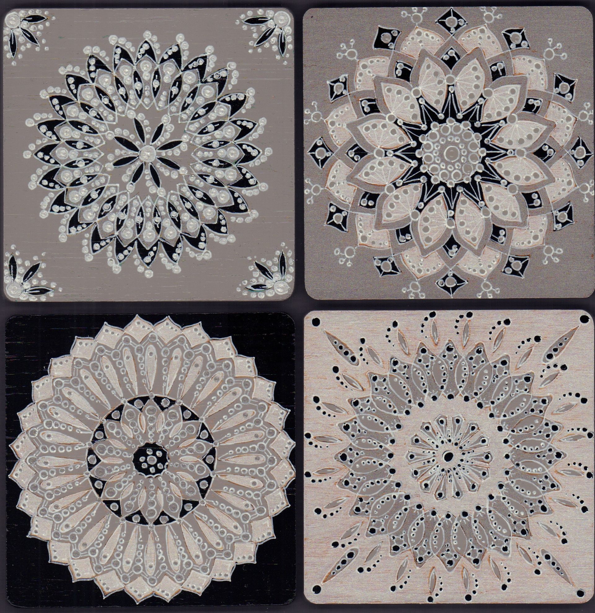 Vier vierkante onderzetters met mandala-ontwerpen in grijs, zwart en wit.