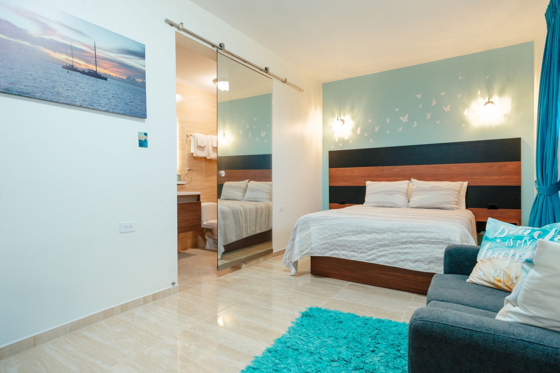 Bright bedroom with bed, sofa, turquoise rug, and mirrored closet door
