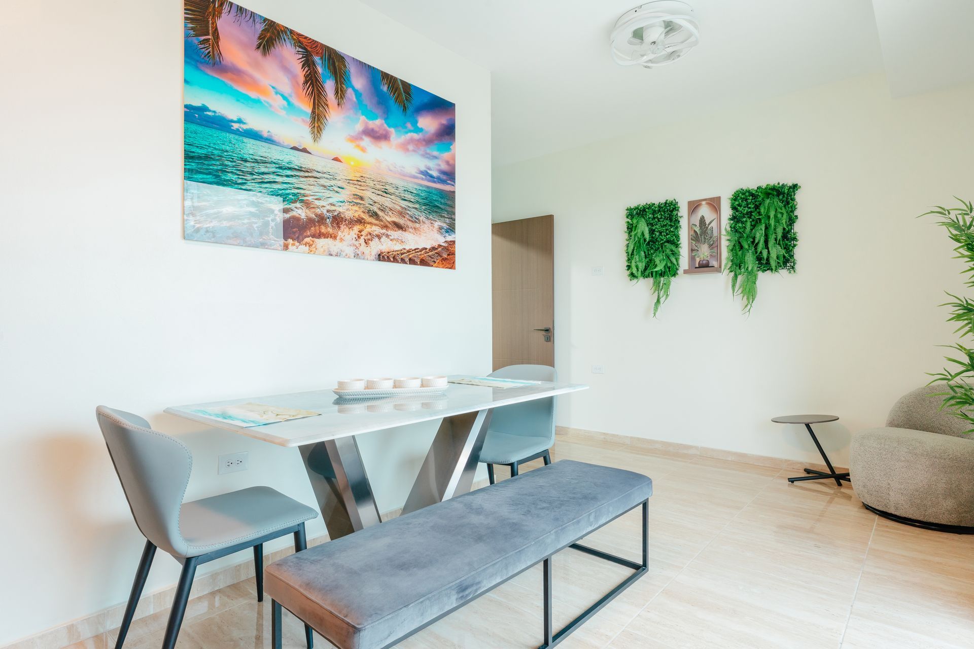 Modern dining room with glass table, gray chairs, bench, beach wall art, and green wall decor