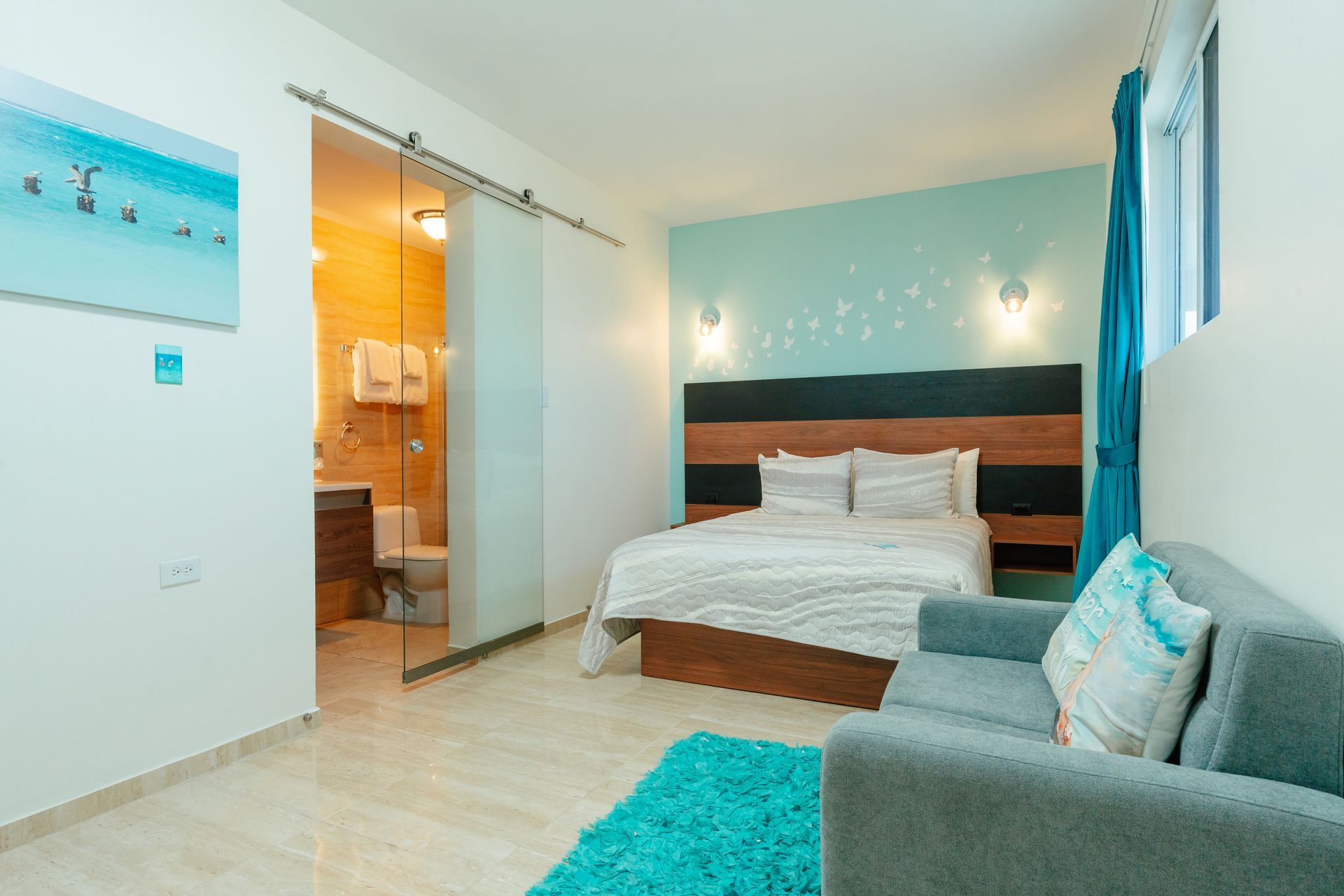 Bright bedroom with a bed, mirrored closet, wooden doors, and a colorful wall painting
