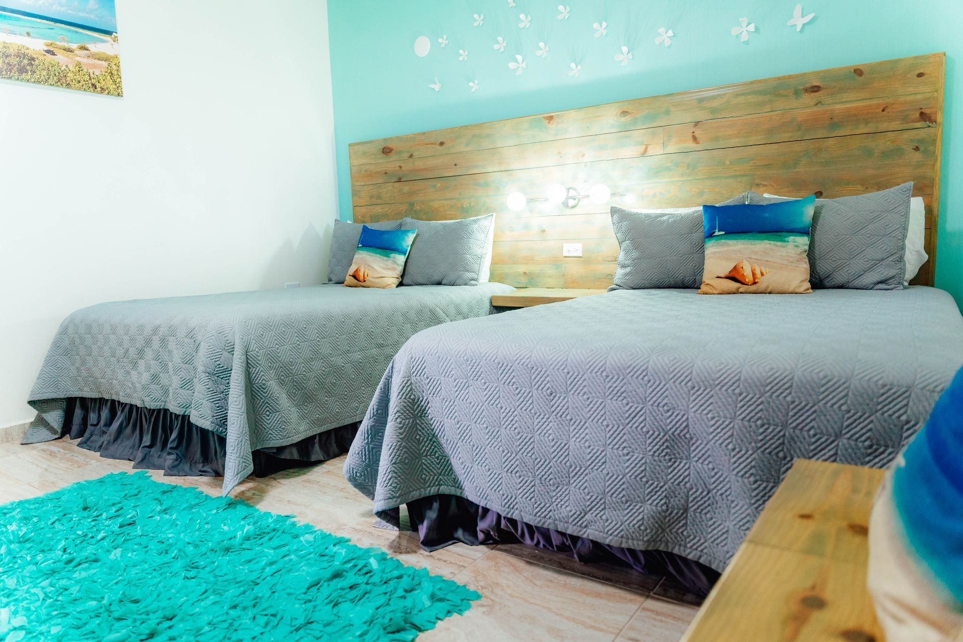 A hotel room with two beds and a blue rug.