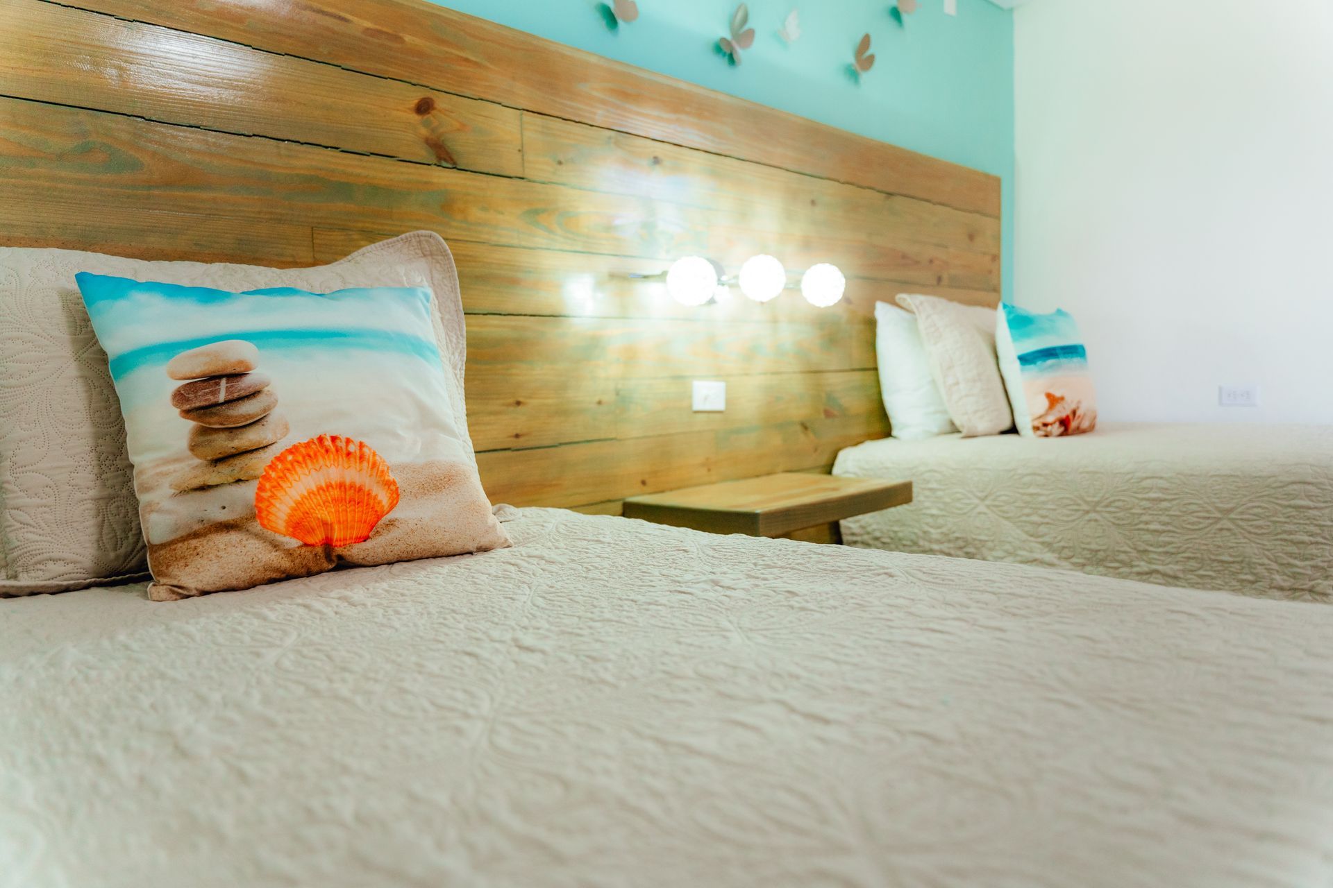 Two neatly made beds with white linens and decorative pillows in a bright hotel room