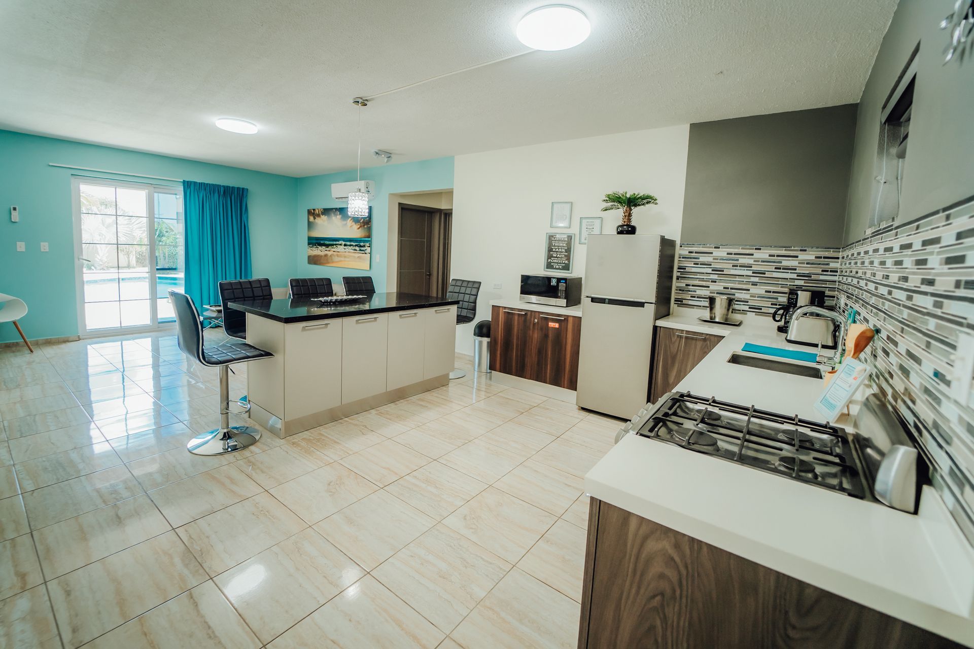 Bright modern kitchen with white tile floor, gray cabinets, island, stove, sink, and blue accent walls