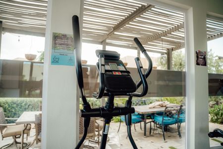 Exercise machine in a bright indoor patio with tables and chairs