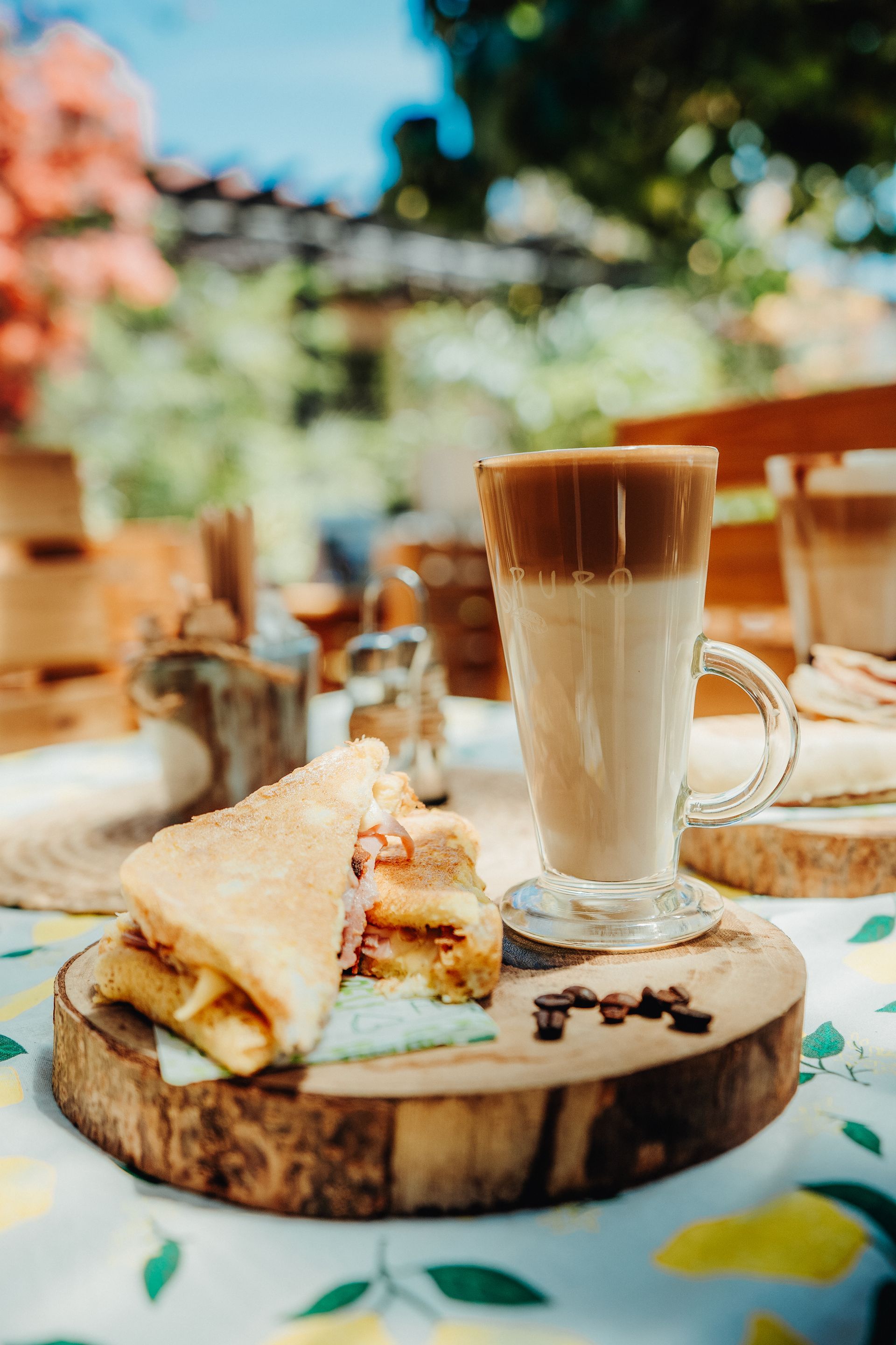 Iced coffee and a pastry on a wooden board at an outdoor café table