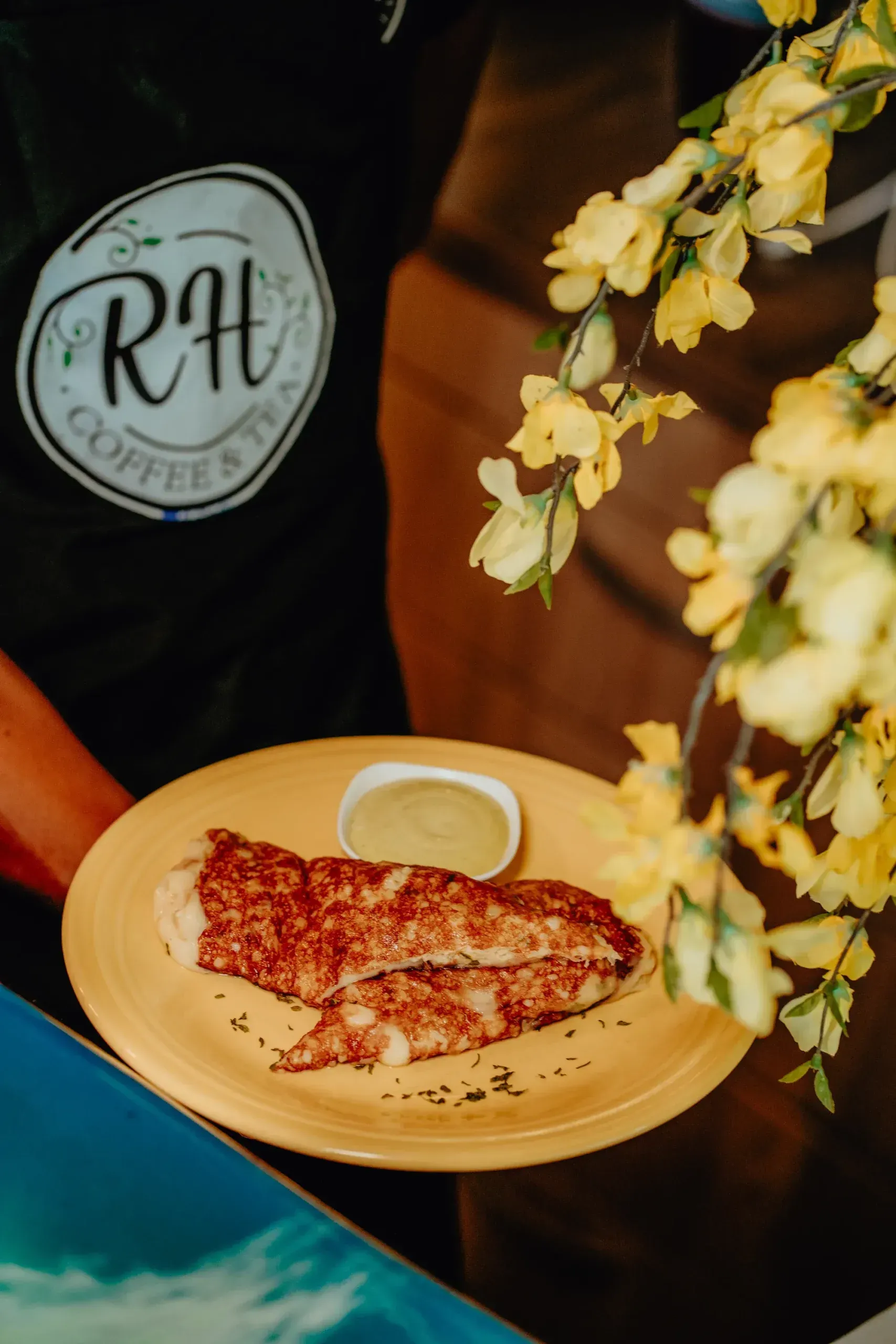 A person is holding a plate of food with a dipping sauce on it.
