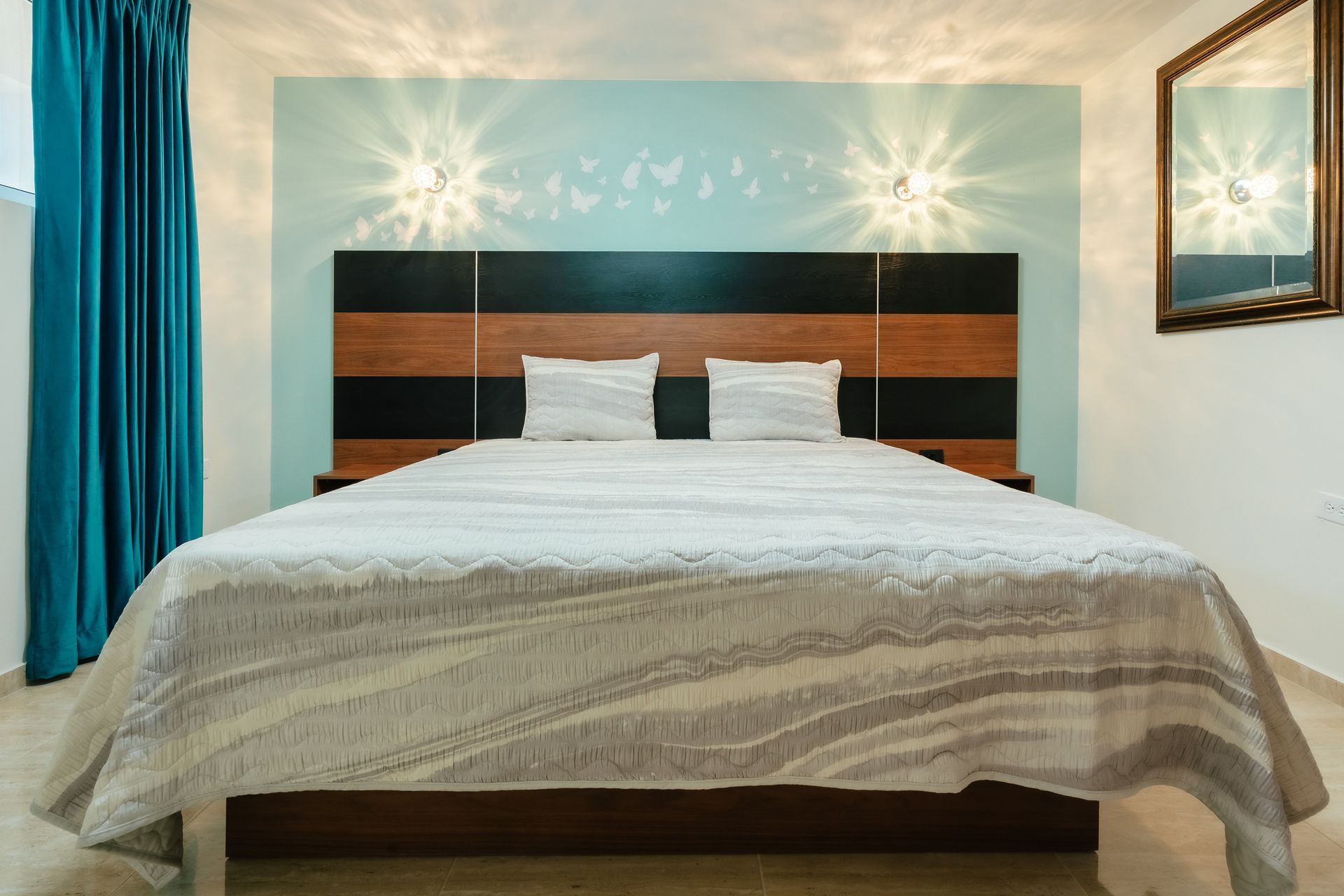 Neatly made bed with white bedding and striped headboard in a bright bedroom