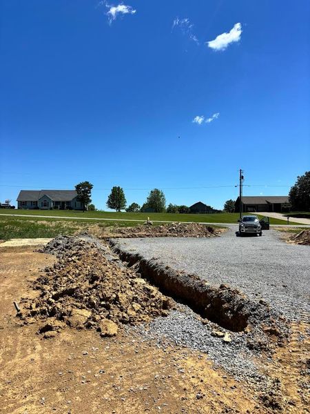 Excavation site with large black pipes laid in a trench beside heavy construction equipment.