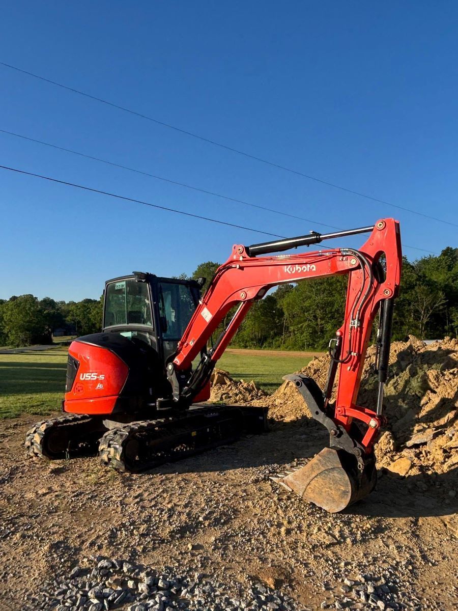 Red excavator on a rocky dirt lot under a clear blue sky