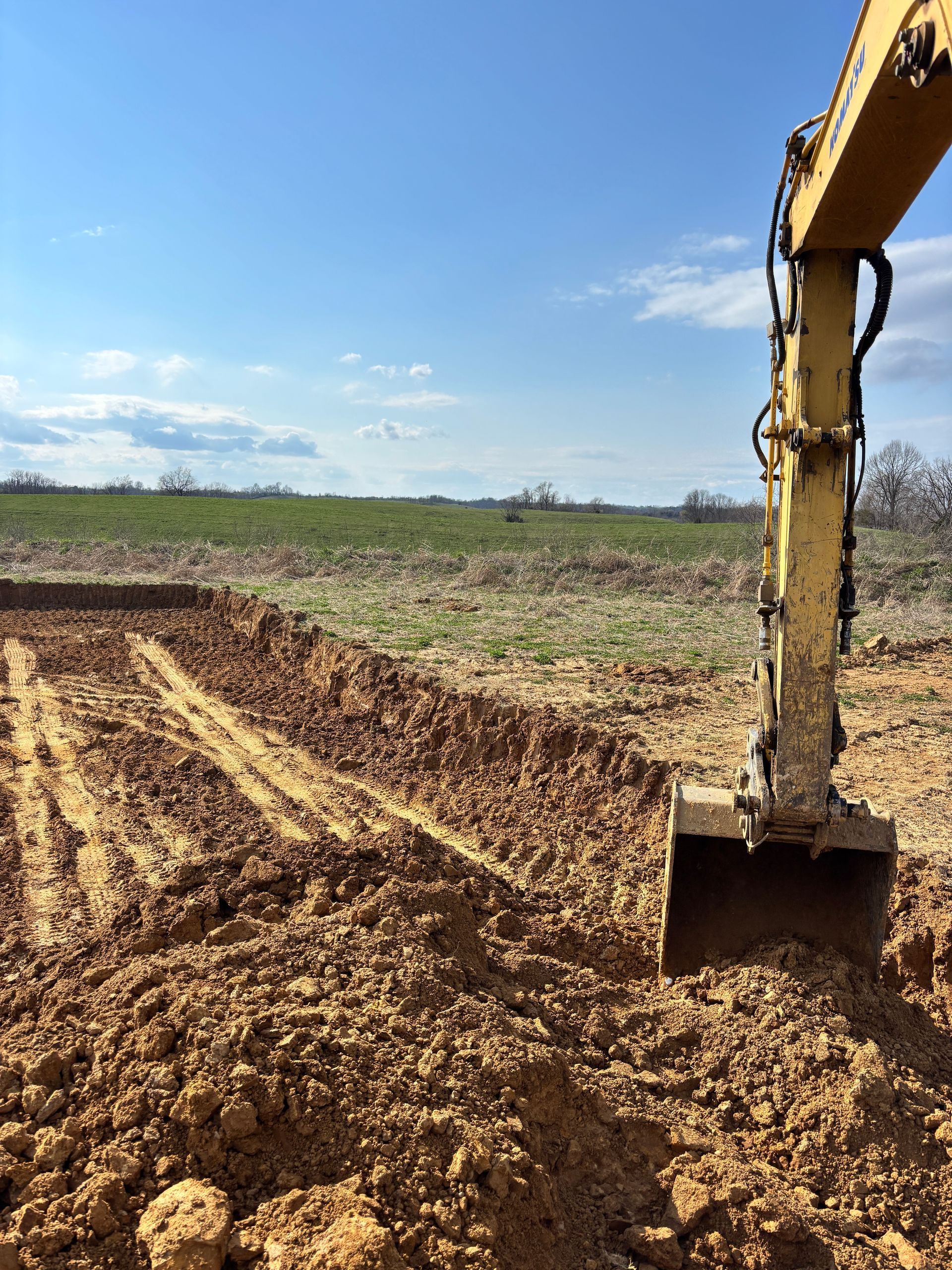 Aerial view of a yellow excavator beside a blue-and-white dump truck on a dirt construction site