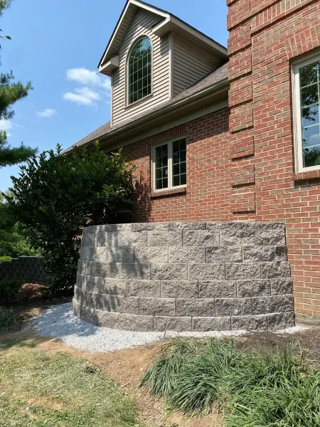 Stone retaining walls and steps in a landscaped outdoor area beside a concrete path.