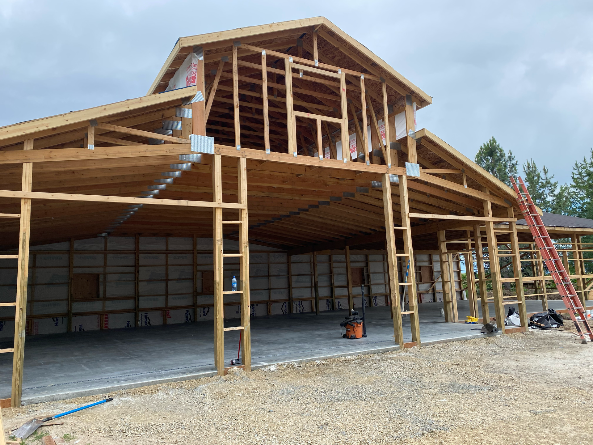 Partially built wooden barn-like structure with open framing and gravel foreground