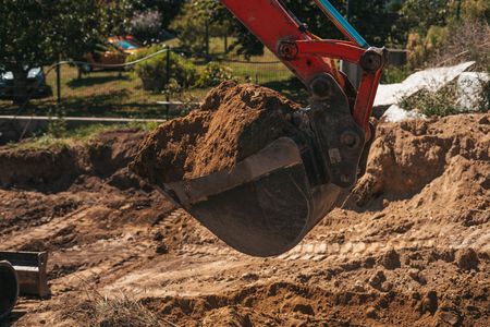 Excavator bucket scooping dirt at a construction site outdoors