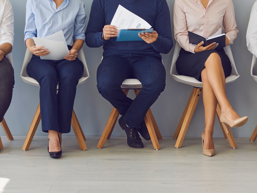 A group of people are sitting in chairs waiting for a job interview.