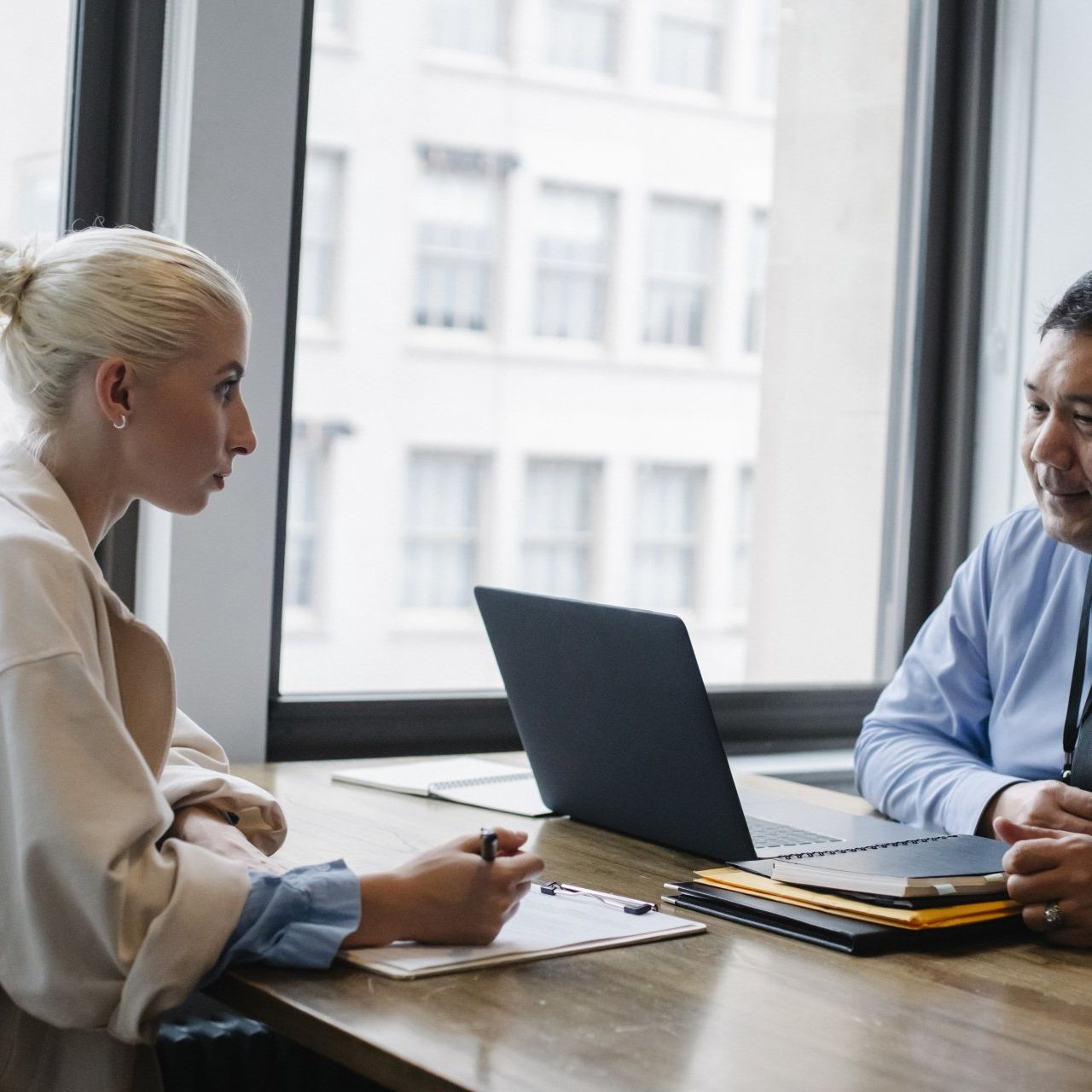 A man and a woman are sitting at a table with a laptop.