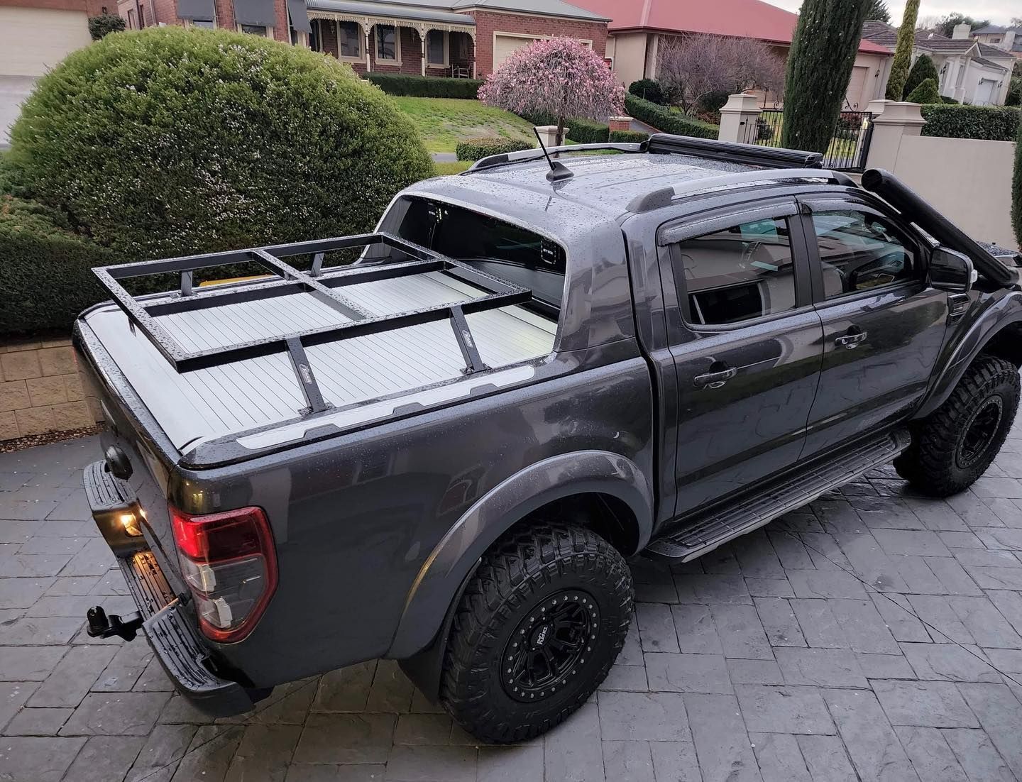 A gray truck with a roof rack is parked in a driveway.