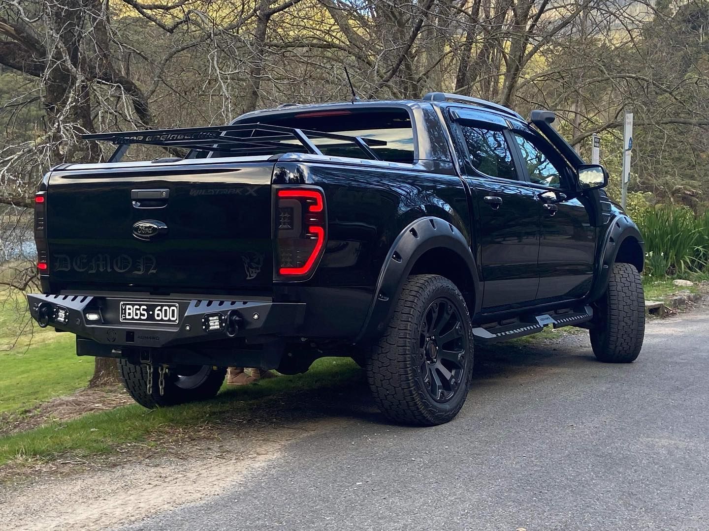 A black ford ranger raptor is parked on the side of the road.