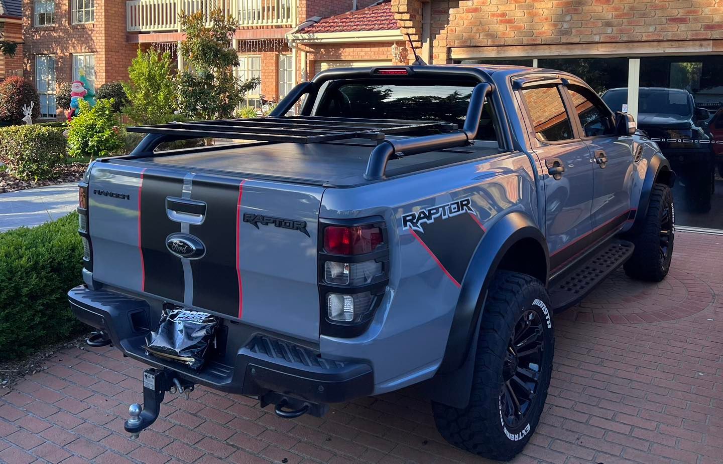 A ford raptor is parked in a driveway in front of a house.
