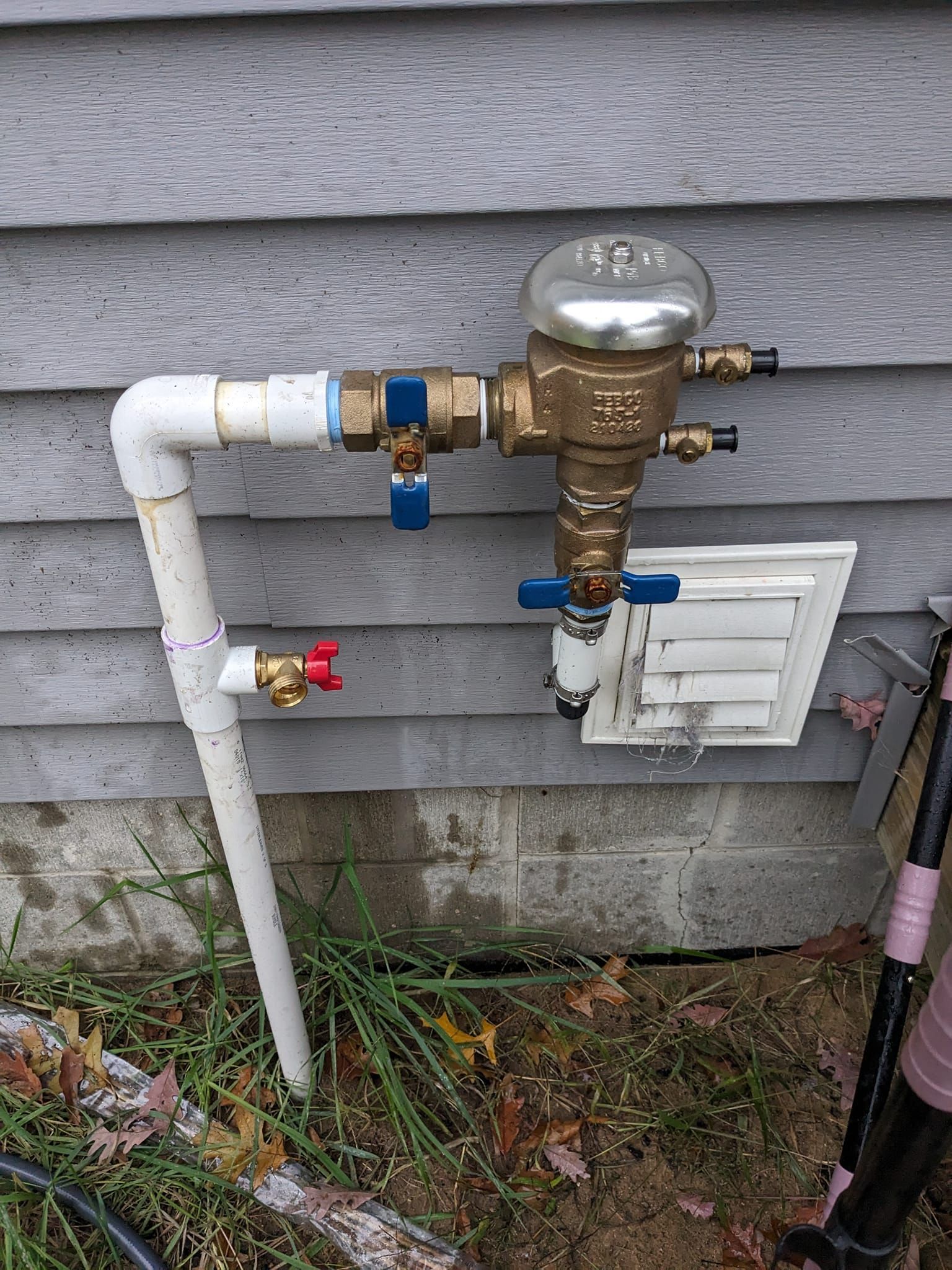 A Pressure Vacuum Breaker (PVB) assembly for an irrigation system mounted on the exterior of a house.