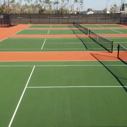 Outdoor pickleball courts with green and orange surfaces and black nets in a sunny setting