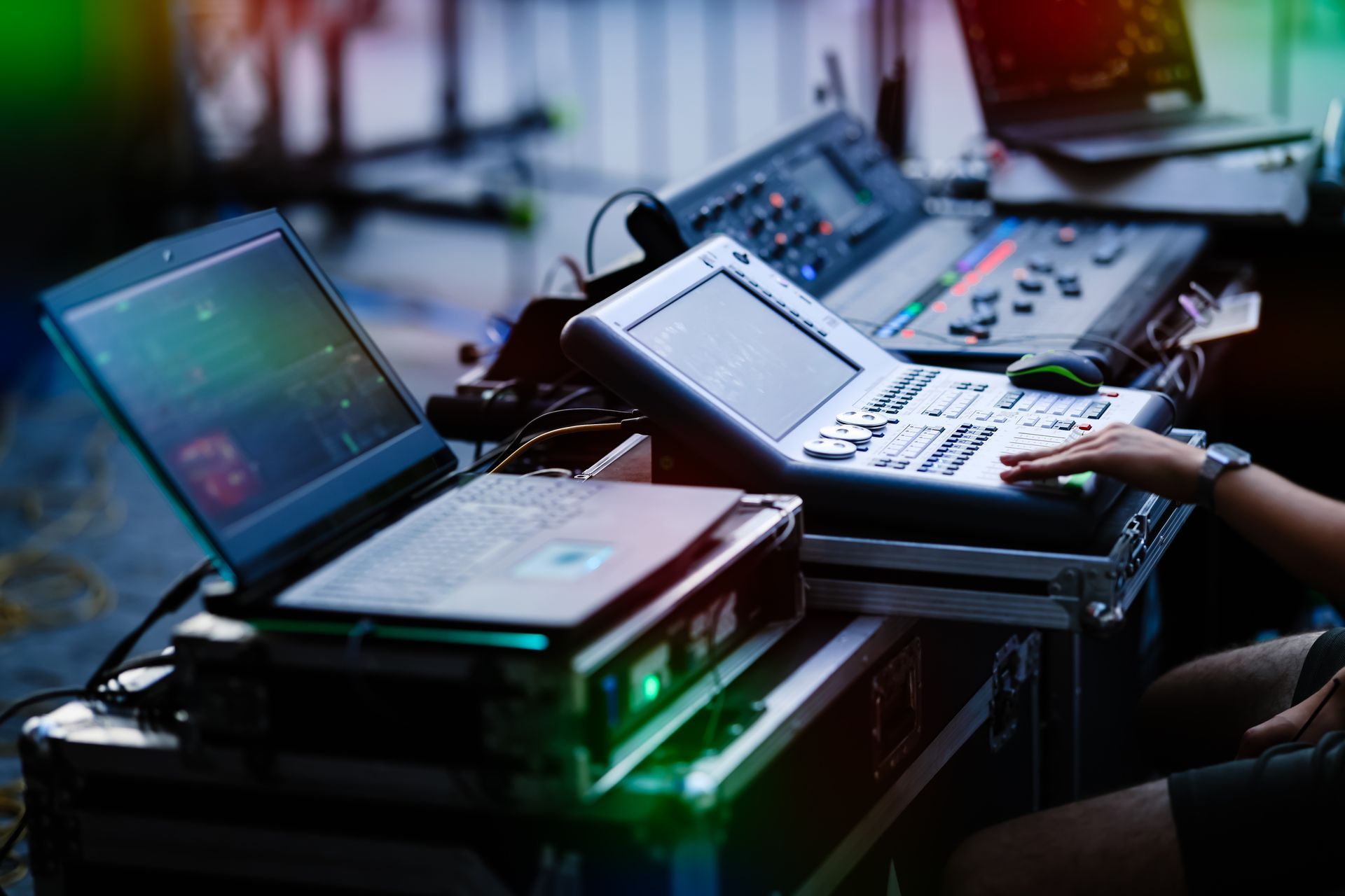 Audio mixing console with laptops and cables on a table in a dimly lit studio