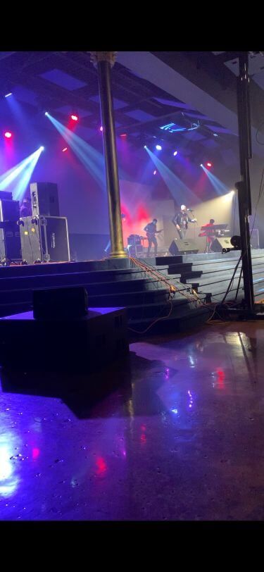 Colorful concert stage with purple and blue lights, stairs, and reflections on the floor