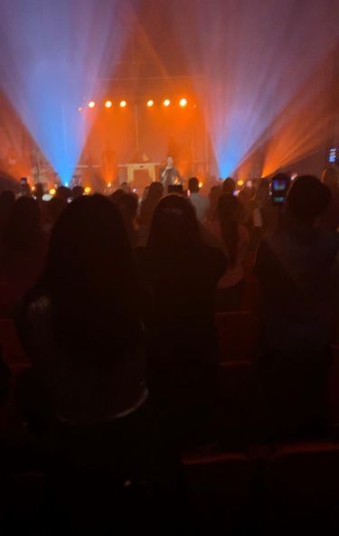 Crowd watching a concert stage lit with orange and blue spotlights