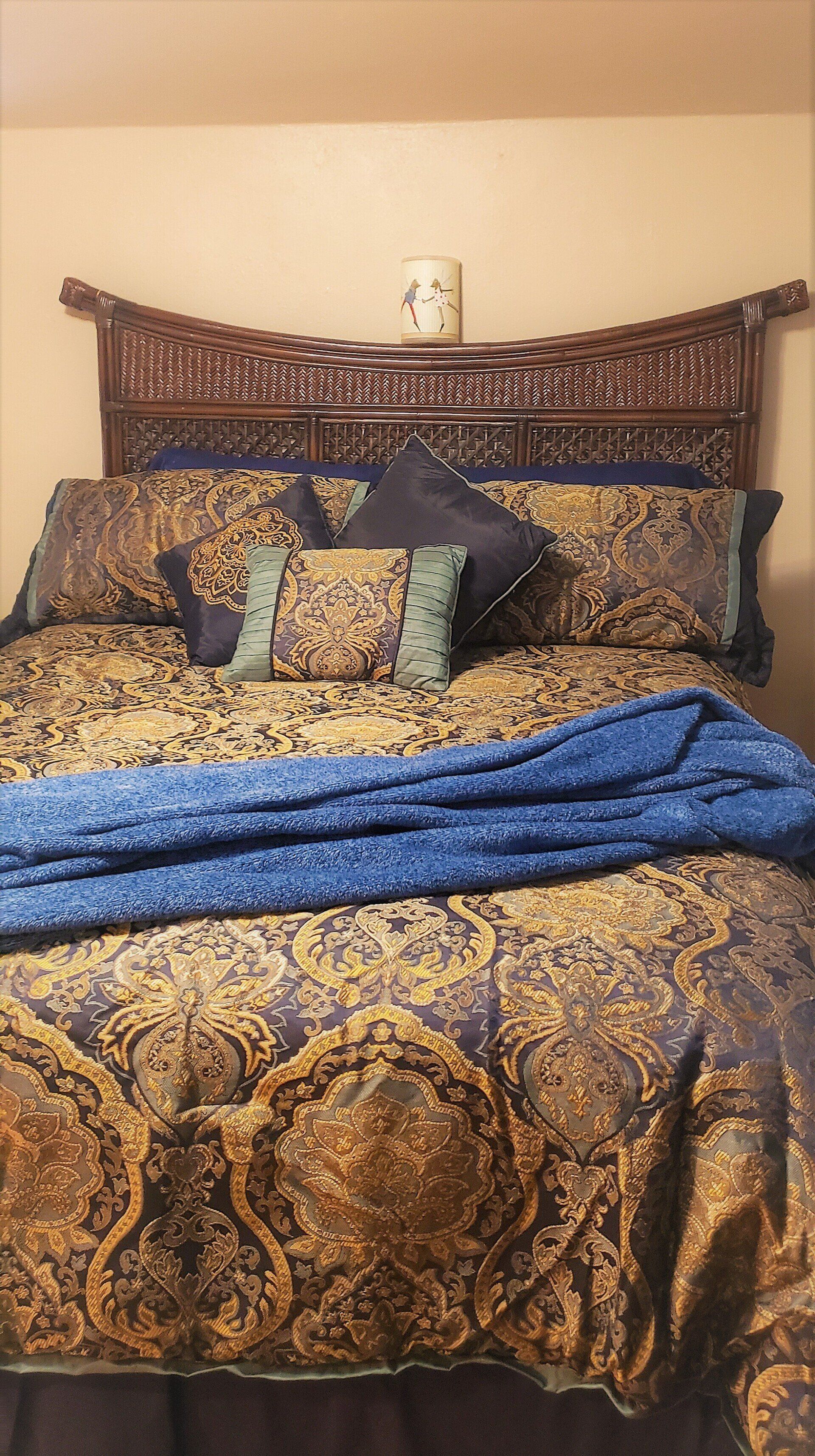 Bed with ornate brown headboard, patterned bedding, and a blue throw.