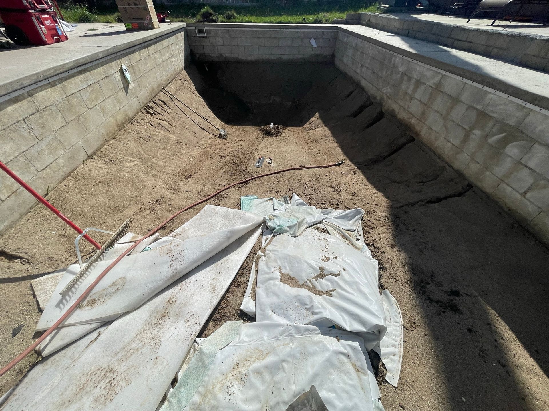 A concrete drainage channel lined with dirt and plastic sheeting, viewed from above.