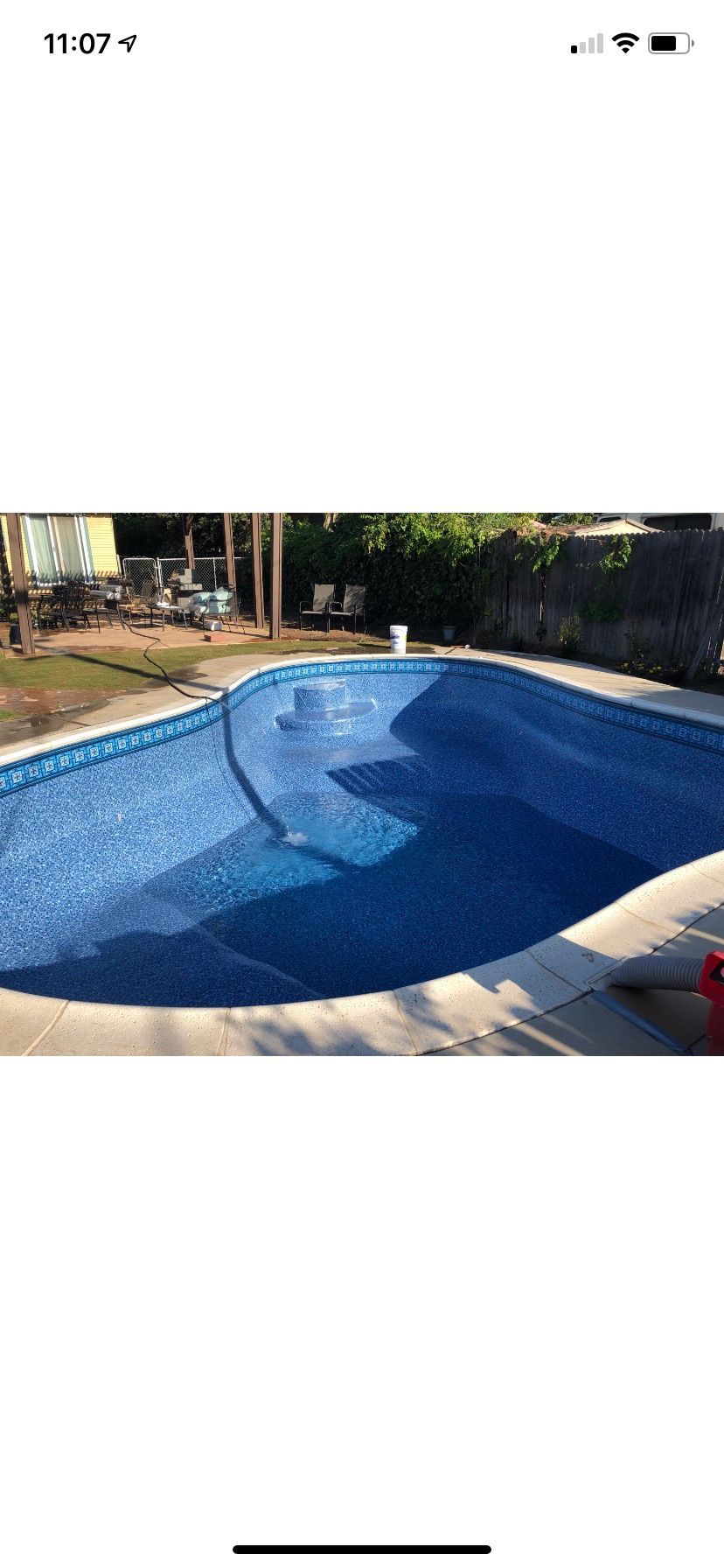 Blue-tiled empty swimming pool with sunlight and shadows, viewed from above