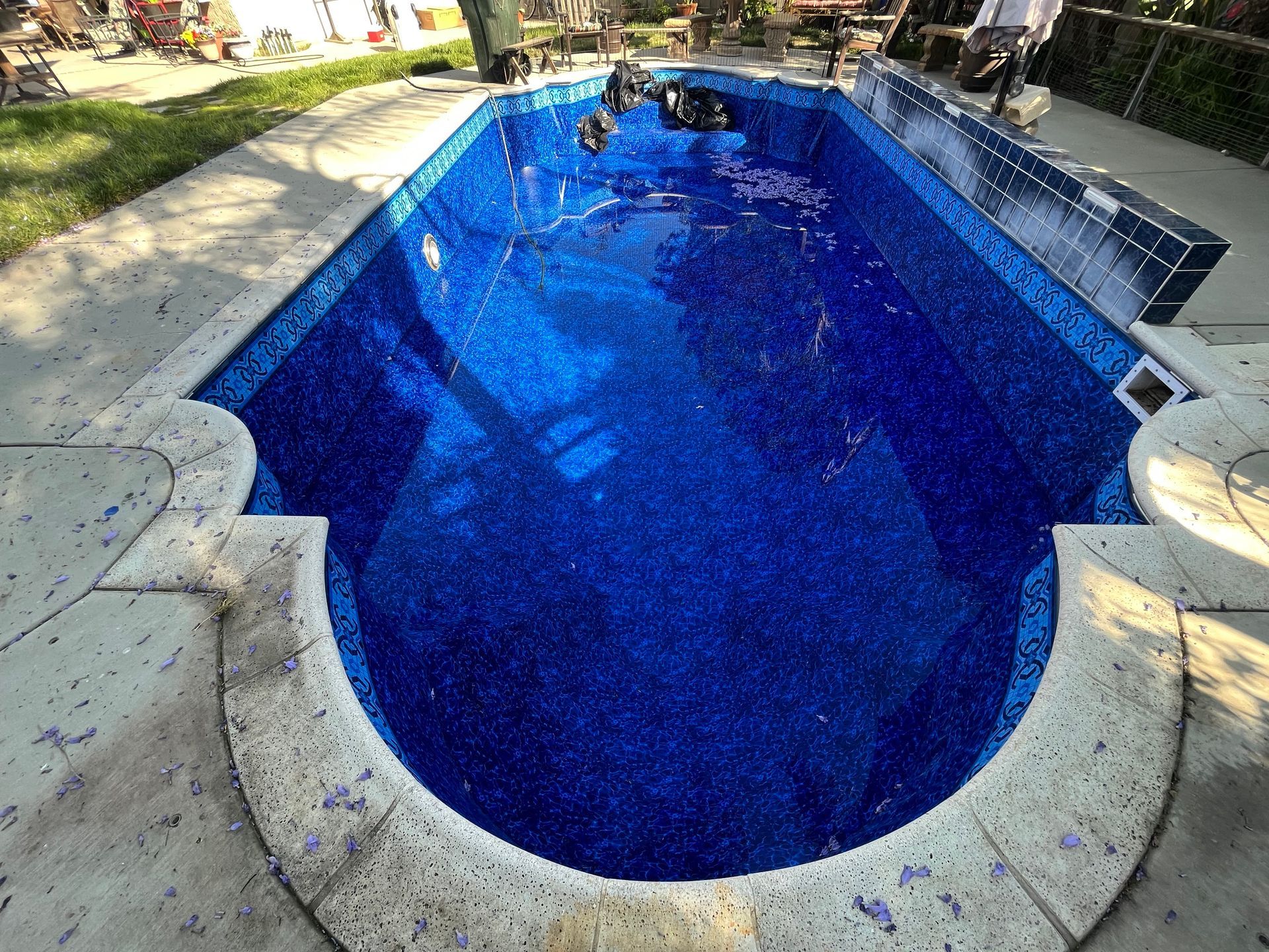 Backyard swimming pool with blue water and stone coping, viewed from above