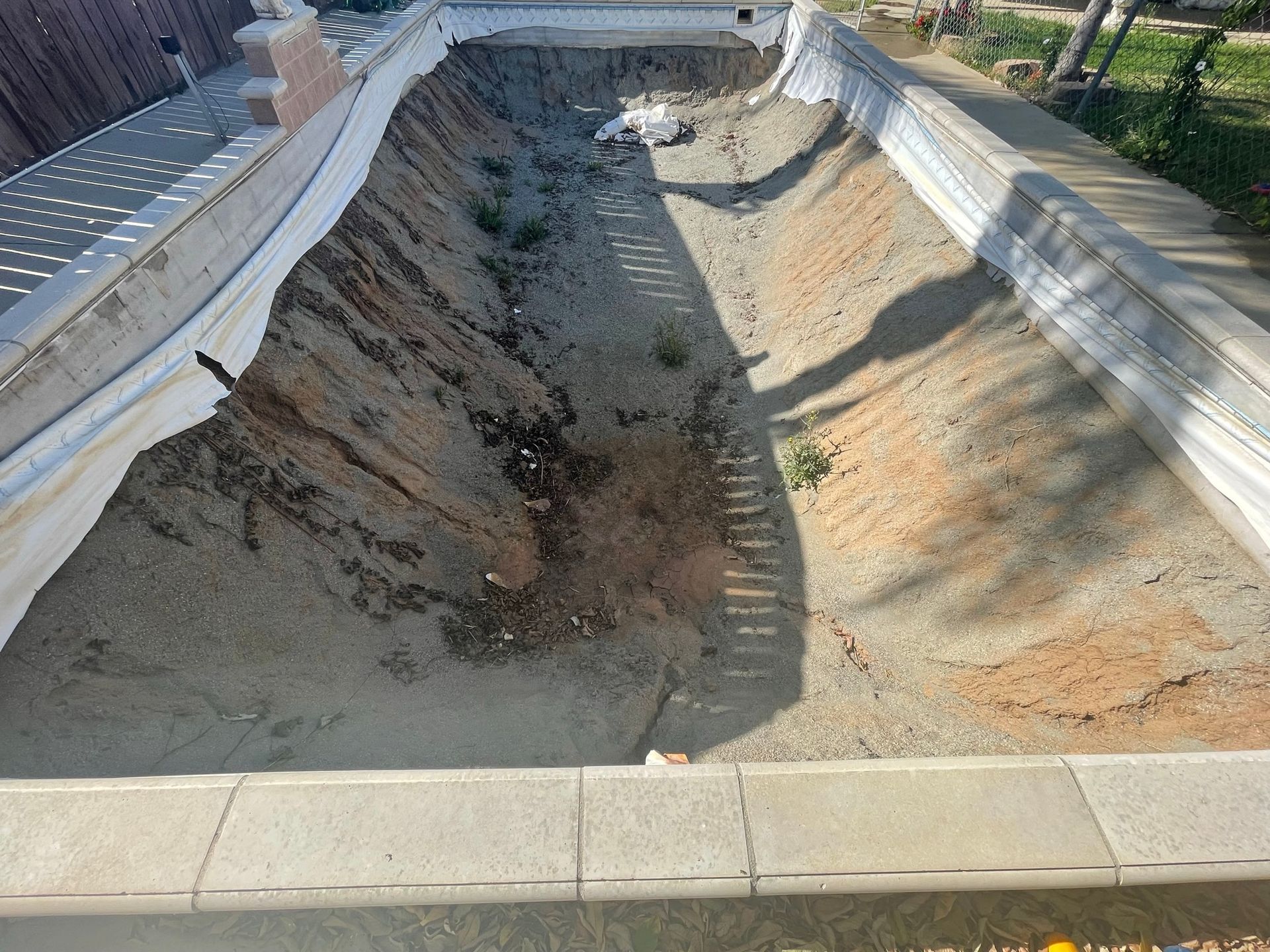 Empty concrete drainage channel under construction with eroded dirt sides and sunlit shadows