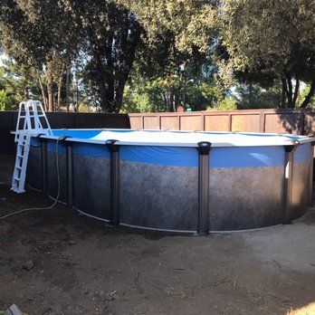 Above-ground pool in a shaded backyard, with a ladder and blue cover partially removed