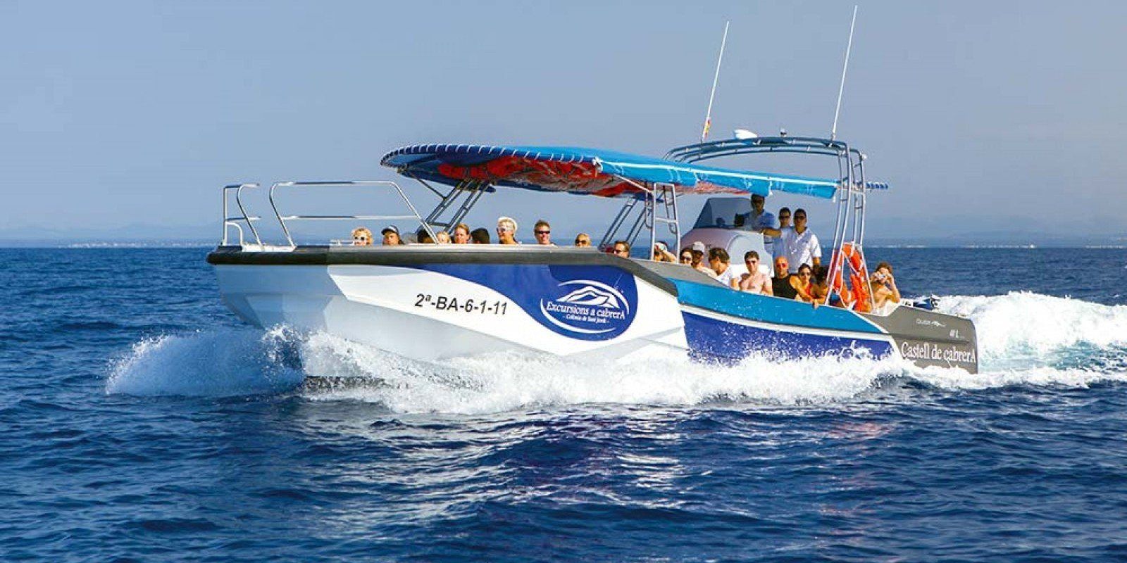 Un barco con gente a bordo flota sobre un cuerpo de agua.