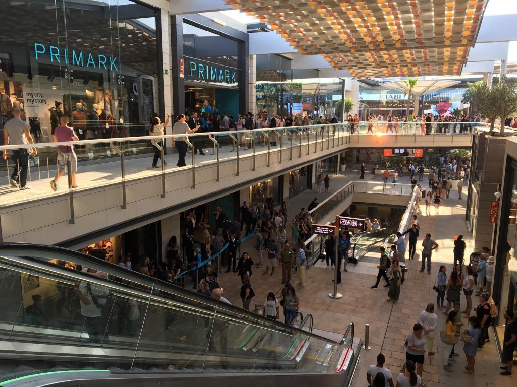 Un grupo de personas baja por una escalera mecánica en un centro comercial.