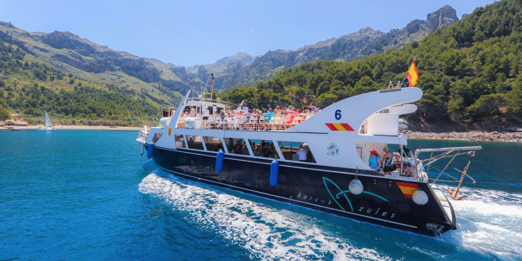 Un barco flota sobre un cuerpo de agua con montañas al fondo.