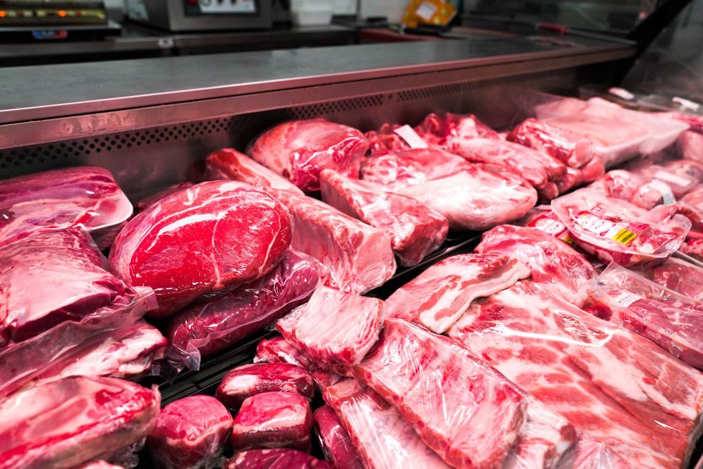 Una vitrina llena de mucha carne cruda en una carnicería.