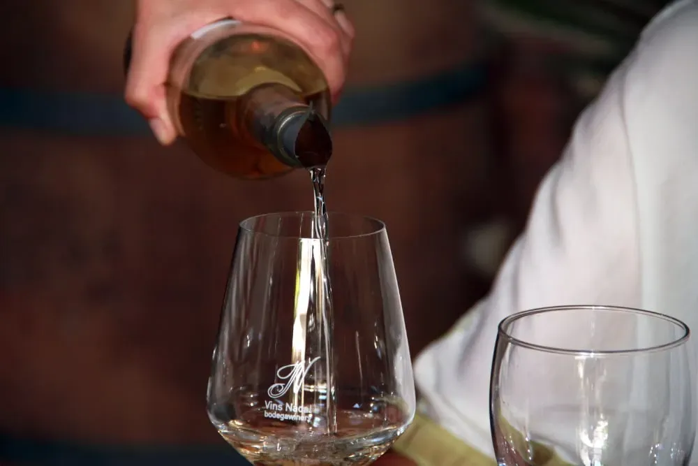 Una persona está sirviendo una copa de vino de una botella.