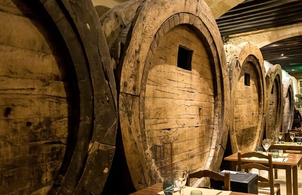 Una fila de barriles de madera están alineados contra una pared en un restaurante.