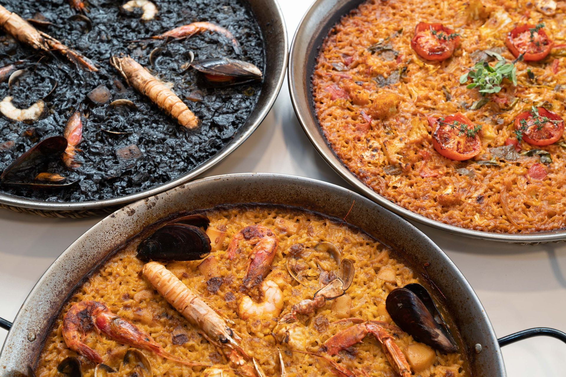 Sobre una mesa hay tres tipos diferentes de paella.