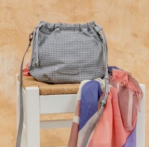 Hay un bolso sobre una silla al lado de una bufanda.