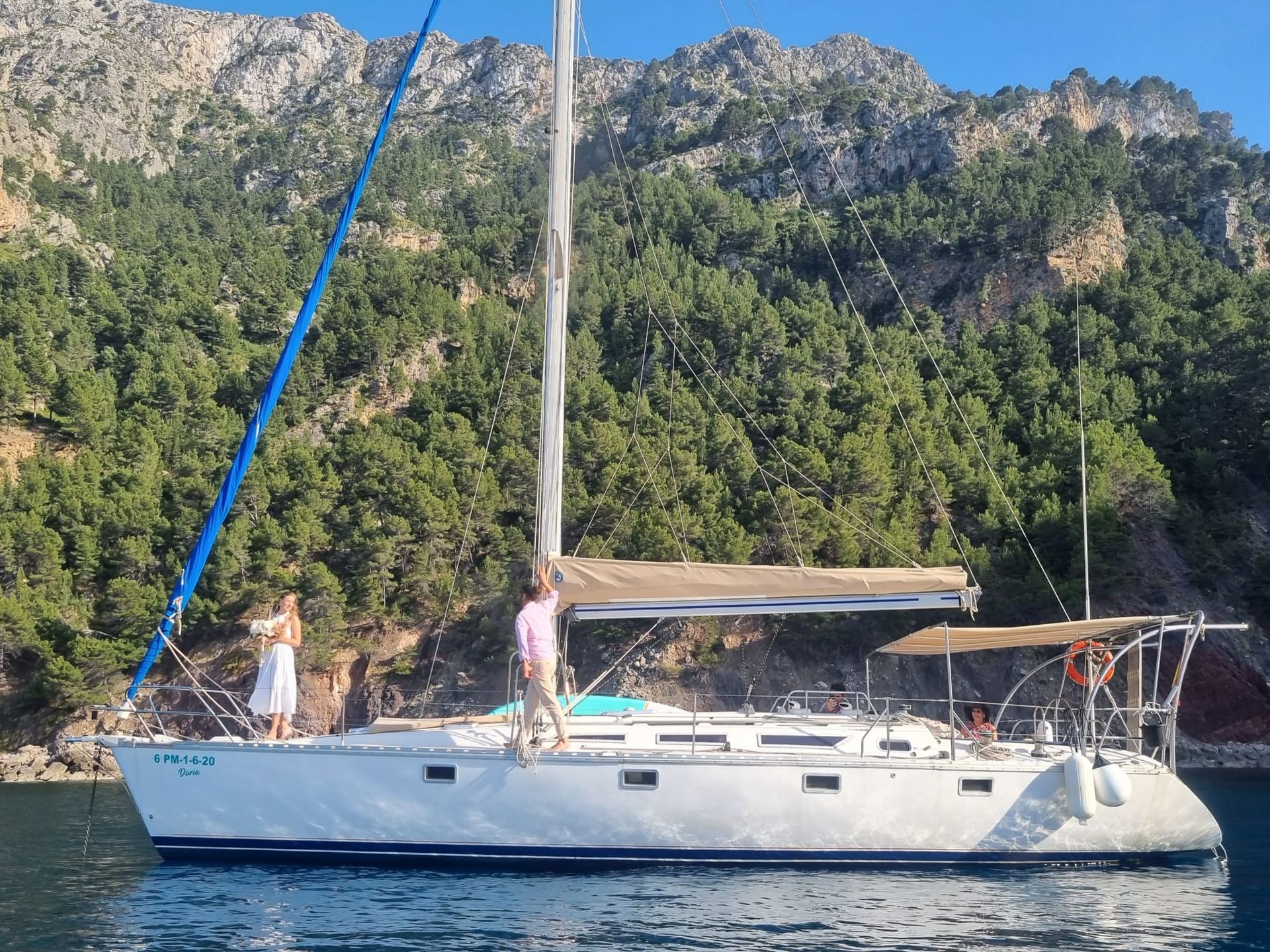 Un velero está atracado en el agua con montañas al fondo.