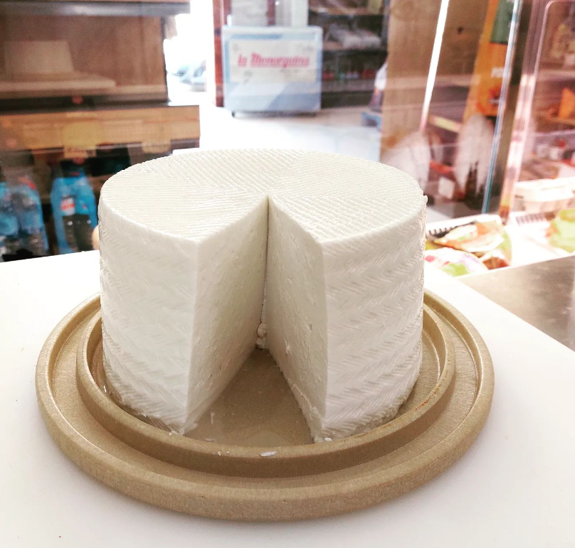 Un trozo de queso está sobre un plato de madera.