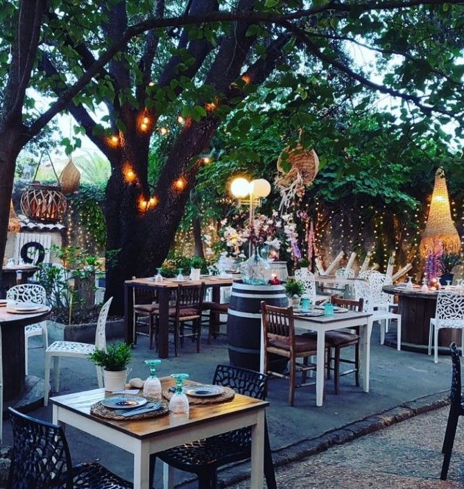 Un restaurante con mesas y sillas debajo de un árbol.
